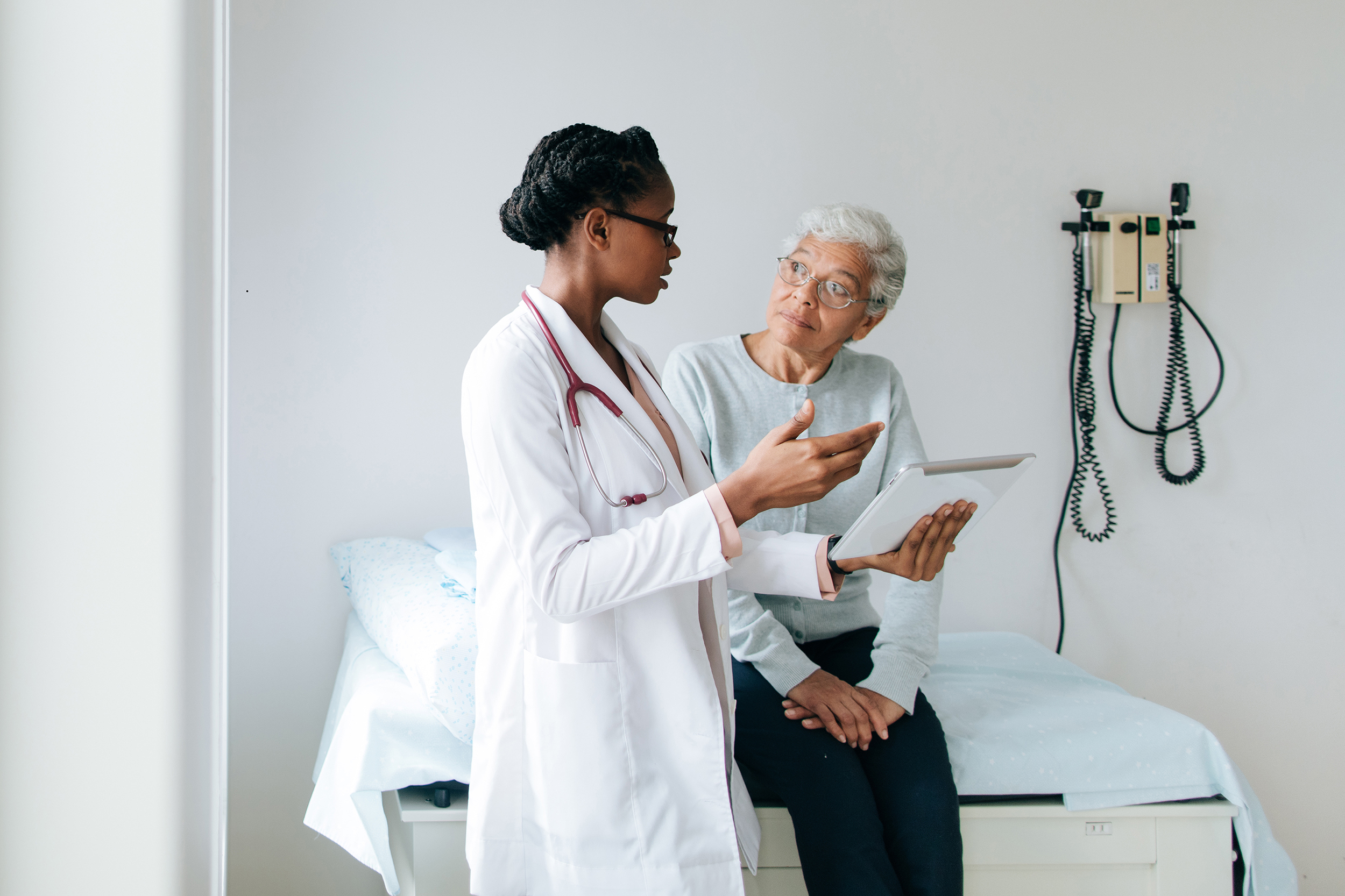 Young female doctor explaining patient with digital tablet