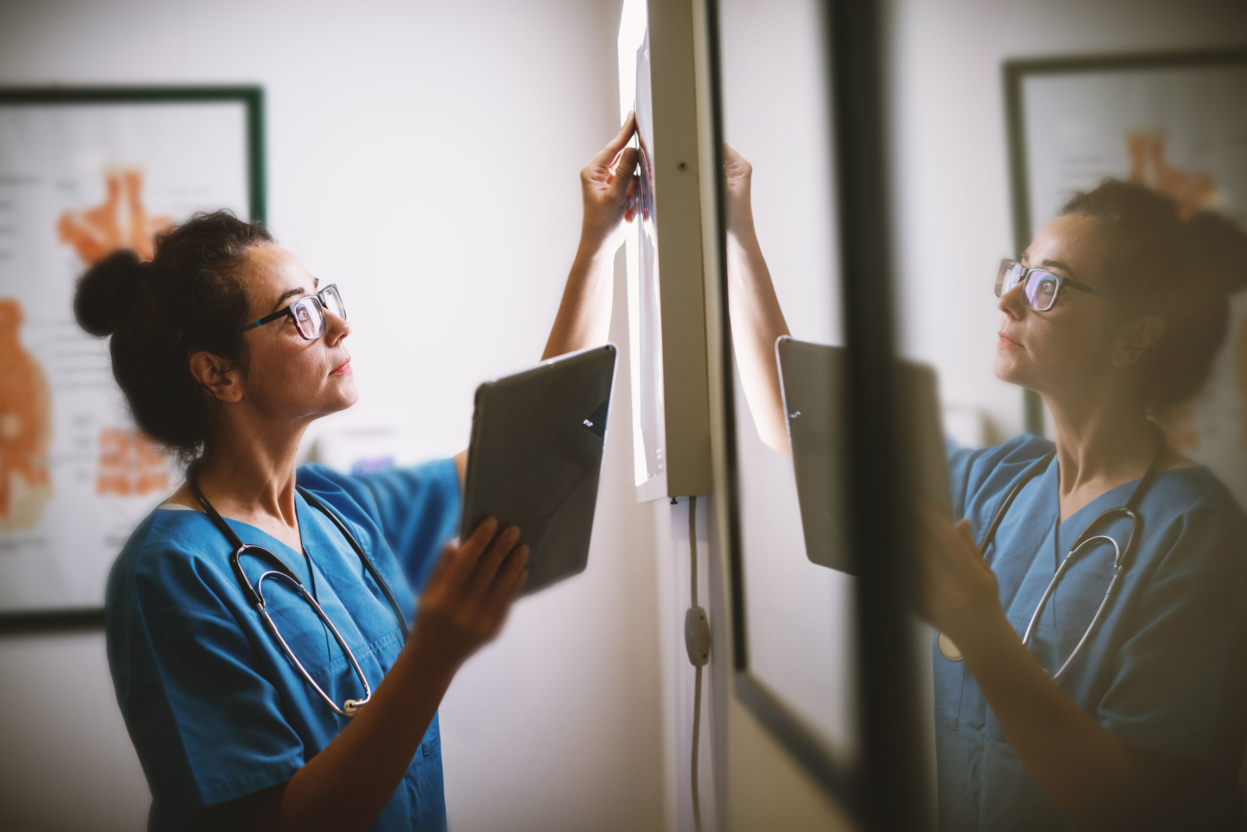 Side view of smiling middle aged nurse checking X-ray